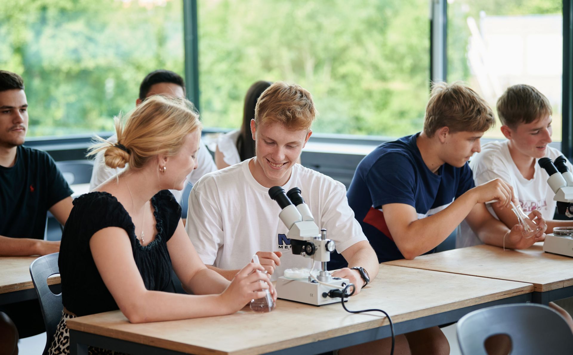 Schüler schauen im Biologie-Unterricht durch ein Mikroskop.